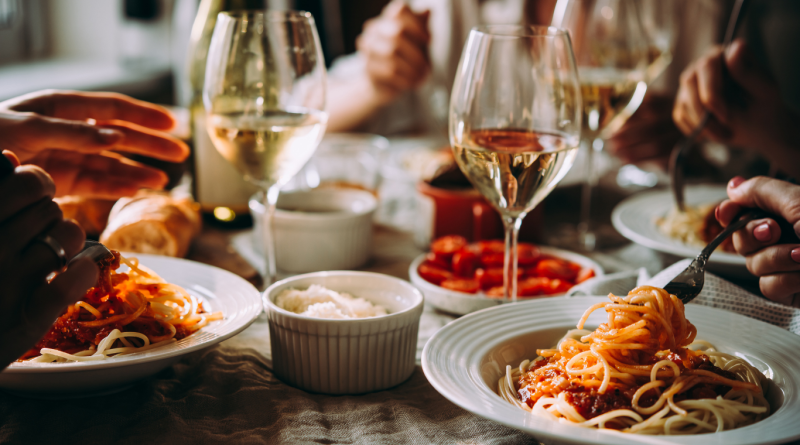 Italian restaurant dinner with spaghetti, wine, and shared dishes on a rustic table.
