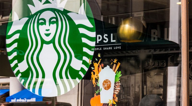 Window display at a Starbucks store featuring the Pumpkin Spice Latte (PSL) promotion with fall-themed illustrations including pumpkins, leaves, and cinnamon sticks, alongside the Starbucks logo.