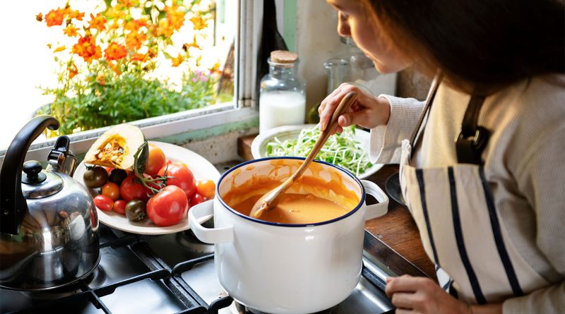 A cozy bowl of autumn soup garnished with herbs, set on a rustic fall-themed table