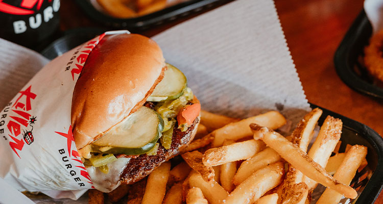 a close-up view of a burger and french fries served in a black plastic basket lined with white paper