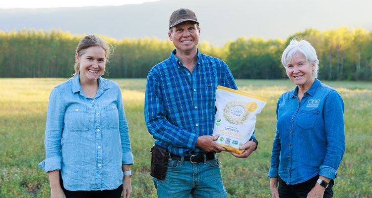 three people standing in a field holding a product